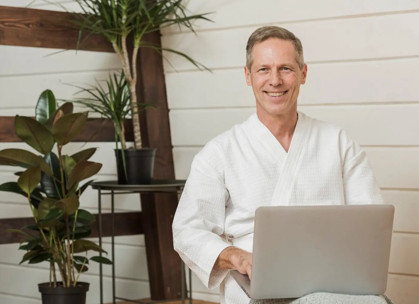 Lächelnder Senior, der an seinem Laptop arbeitet.